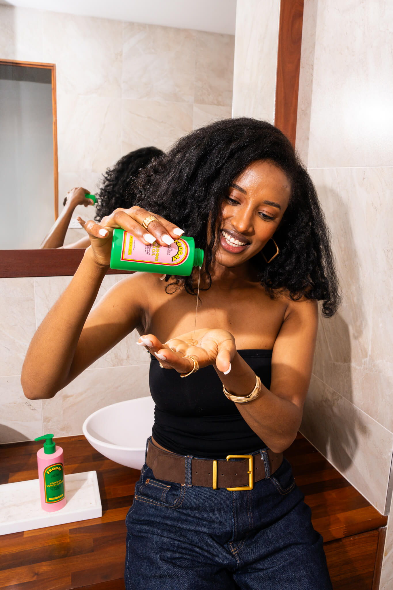 Woman applying Froday hair oil to curly hair (shine and moisture)