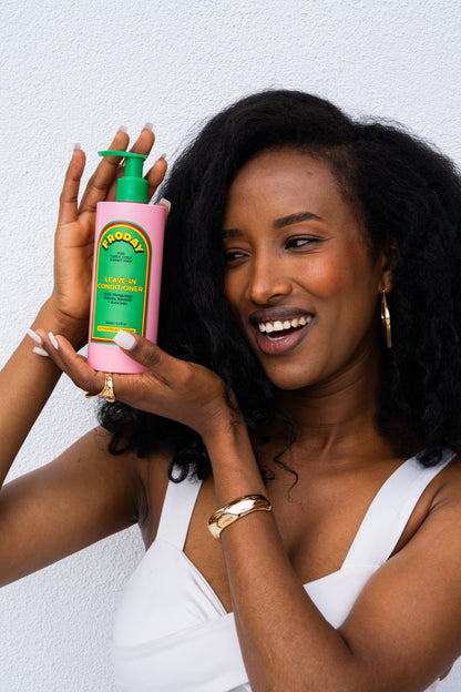 Smiling woman holding Froday leave-in conditioner bottle (natural curls)