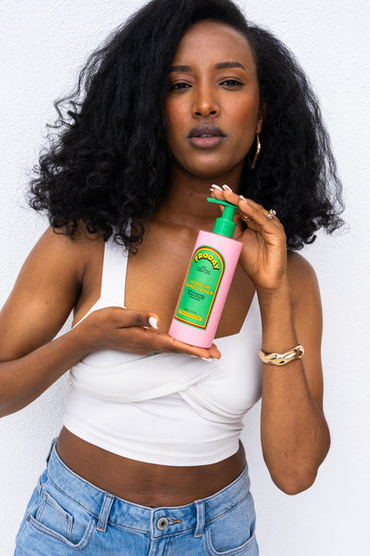 Woman holding Froday leave-in conditioner with defined curls