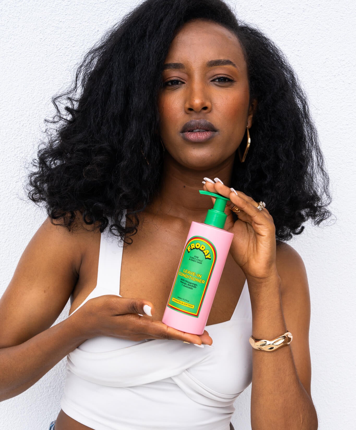 Woman with natural curls holding Froday hydrating leave-in conditioner